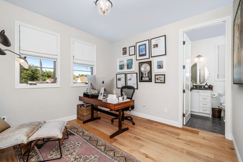 Habitación minimalista con escritorio, silla y lámpara con piso de madera en casa de Puebla, México.